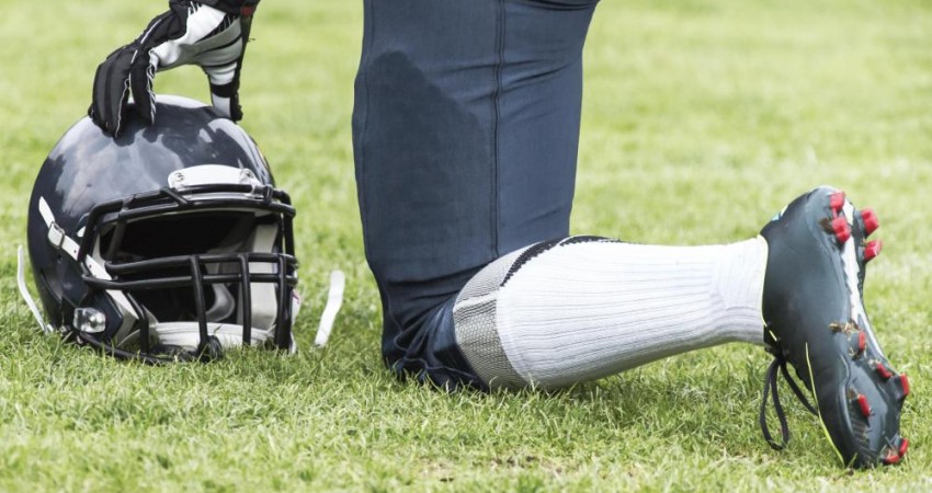 football-player-kneeling-with-helmet-off